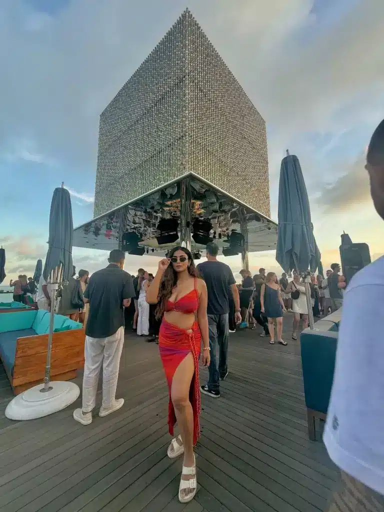 : A woman poses at a popular, chic beach club in Bali, representing the superficial "influencer's personality" layer of the island. This limited experience can make visitors wrongly conclude Bali is boring.