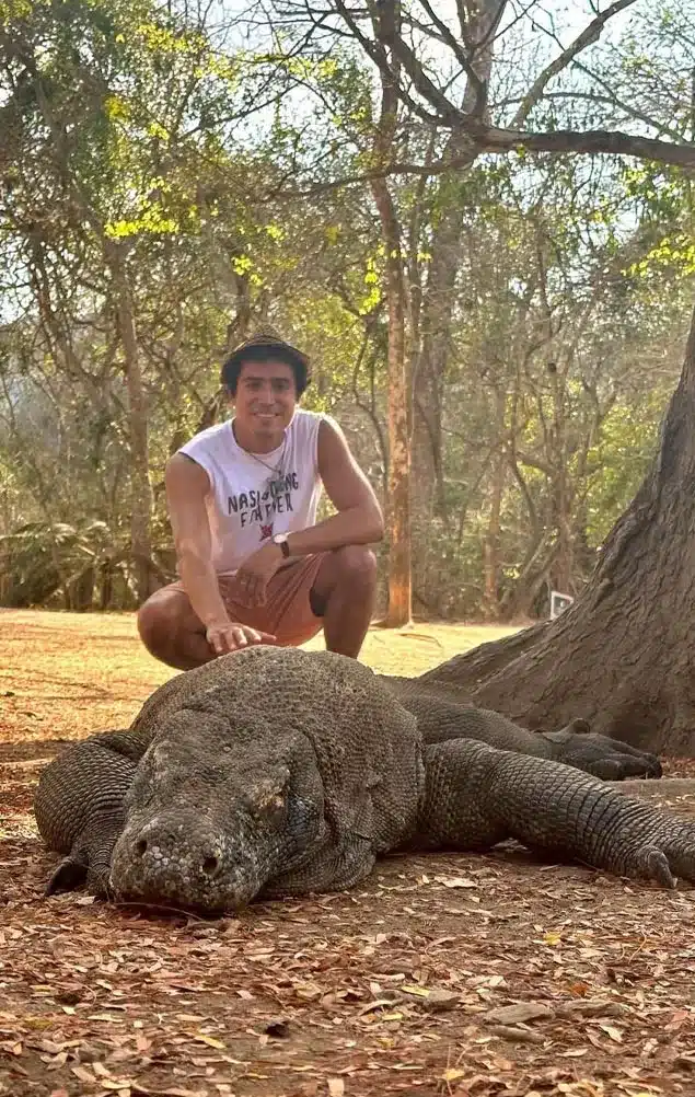 photo of one of hey bali's guests taking a photo with a komodo dragon while taking part in the komodo tour package from bali